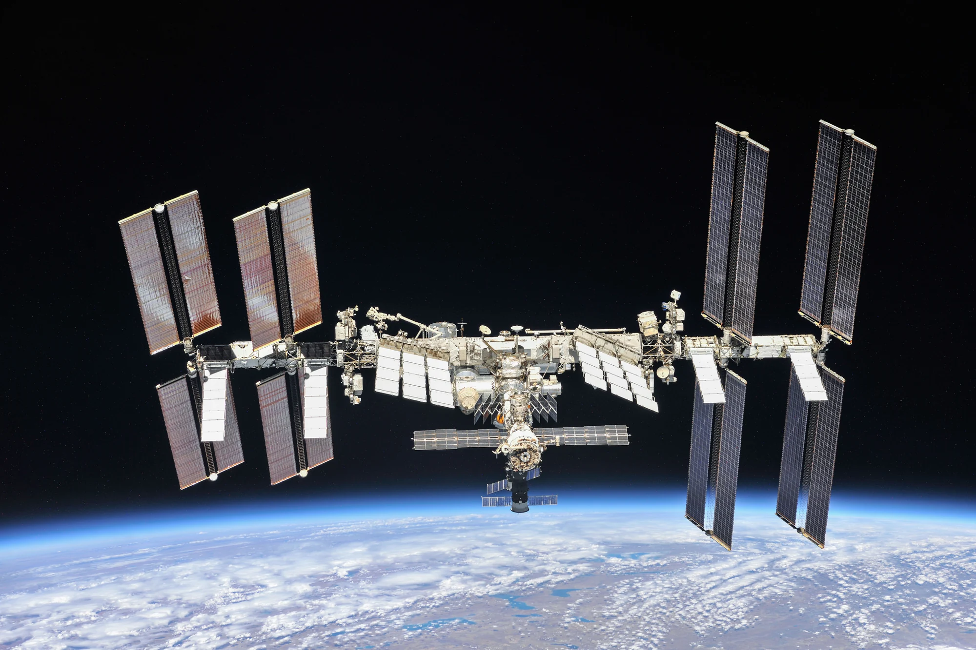 NASA照片中的国际空间站，太阳能电池阵列展开，下方是地球弧线